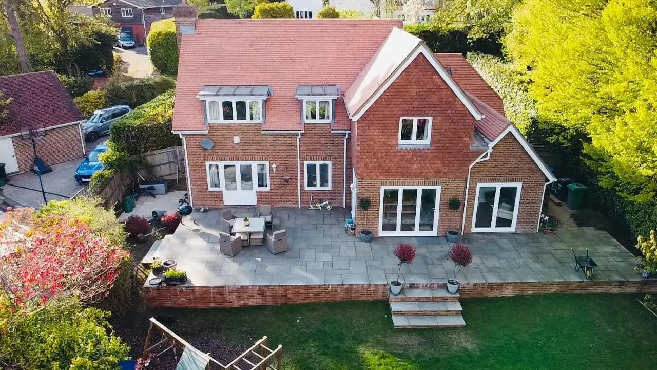 Elevated view of a brick house with a paved rear terrace and garden steps
