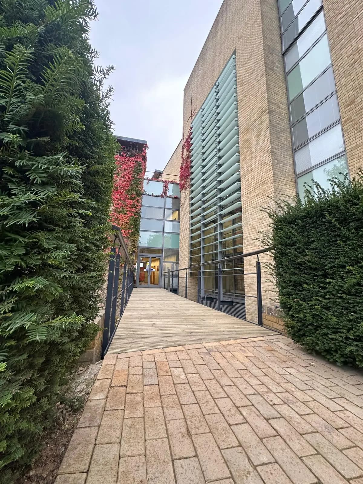 Brick and glass building with a timber entrance walkway and metal railings